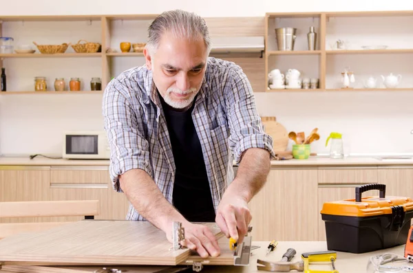 Mutfakta çalışan yaşlı bir tamirci. — Stok fotoğraf