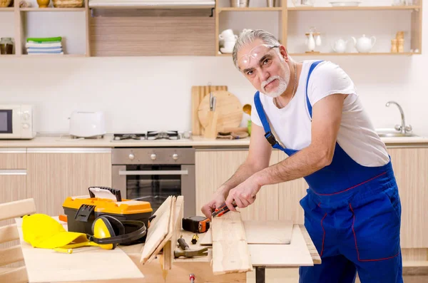 Reparador de empreiteiro envelhecido que trabalha na cozinha — Fotografia de Stock