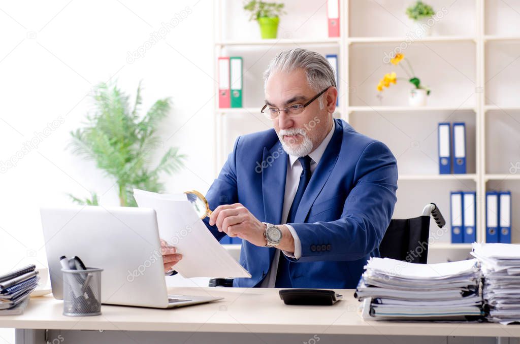 Aged employee in wheelchair working in the office