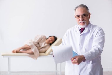 Genç hastayı muayene eden yaşlı erkek doktor psikiyatristi