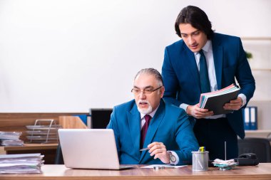 Genç ve yaşlı çalışanlar ofiste birlikte çalışıyorlar.
