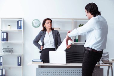 Yaşlı kadın patron ve genç erkek çalışan ofiste.