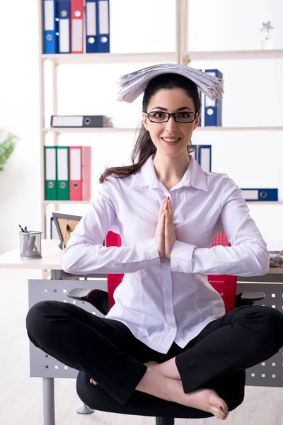 Young female employee doing exercises in the office