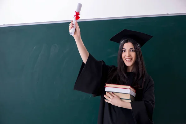 Female graduate student in front of green board — Stock Photo, Image