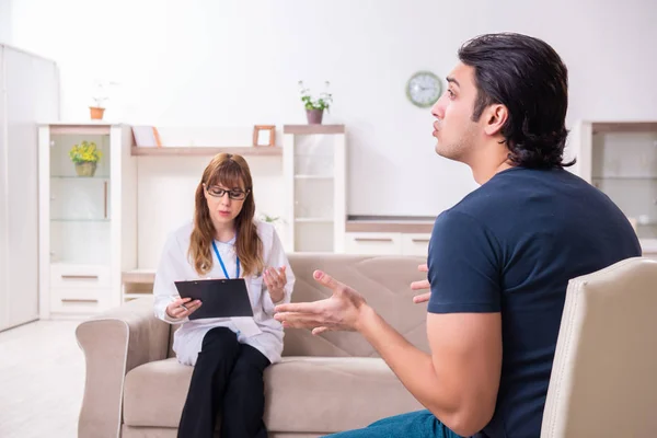Jonge mannelijke patiënt in gesprek met vrouwelijke psycholoog persoonlijk — Stockfoto