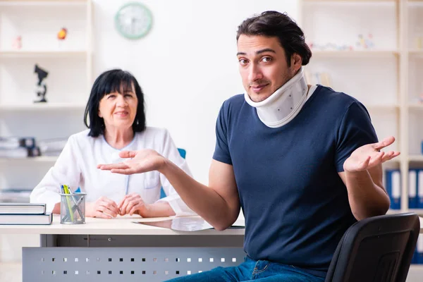 Junge männliche Patientin besucht betagte Ärztin — Stockfoto