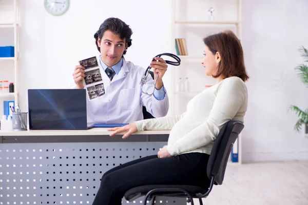 Vieja embarazada visitando joven médico masculino — Foto de Stock