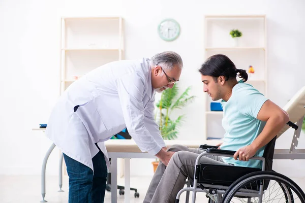 Paciente masculino en silla de ruedas visitando a un viejo médico — Foto de Stock