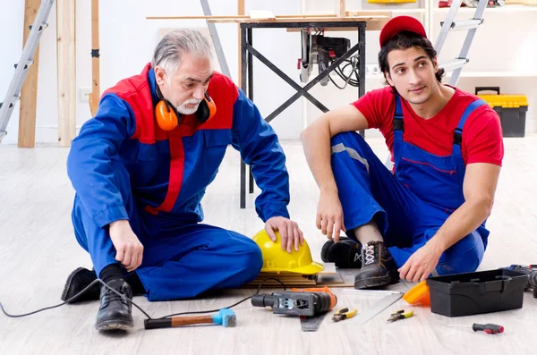 Two professional contractors laying flooring at home