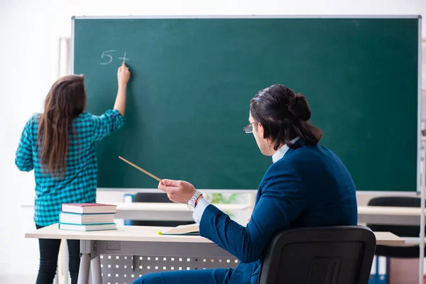 Young handsome teacher and female student in the classroom — Stock Photo, Image