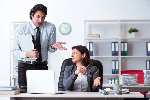 Oude vrouwelijke baas en jonge mannelijke werknemer in het kantoor — Stockfoto