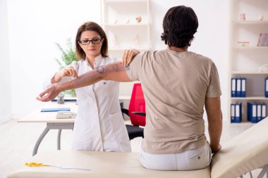 Kadın doktor hastaları goniyometre ile kontrol ediyor.