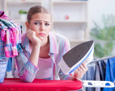 Üzücü kadın evde kıyafetleri ütülüyor.