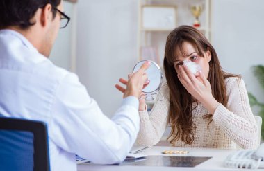 Erkek doktor burun ameliyatı olan bir hastayla konuşuyor.