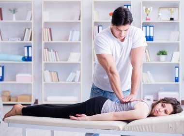 Genç doktor kayropraktik uzmanı kadın hastaya masaj yapıyor.