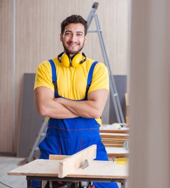 Genç bir marangoz dairesel testereyle odun kesiyor.