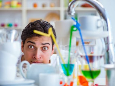 Bulaşıkları yıkamaktan bıkmış bir adam.