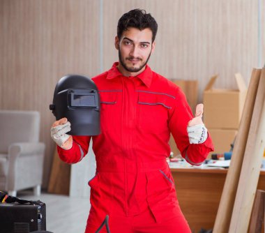 Kaynak tabancası elektrot ve kask takan genç bir tamirci.