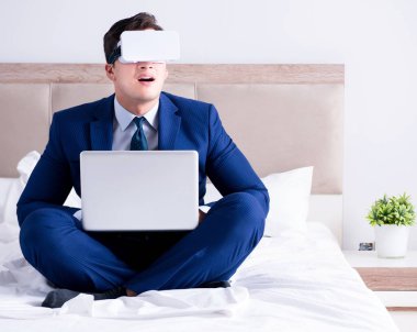Yatak odasında sanal gerçeklik kulaklığı takan bir iş adamı.