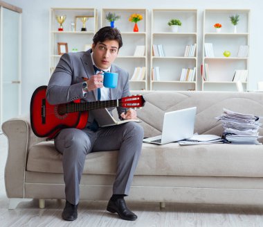 Evde gitar çalan bir iş adamı.