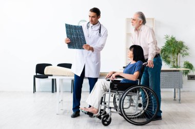 Yaşlı çift genç erkek doktoru ziyaret ediyor.