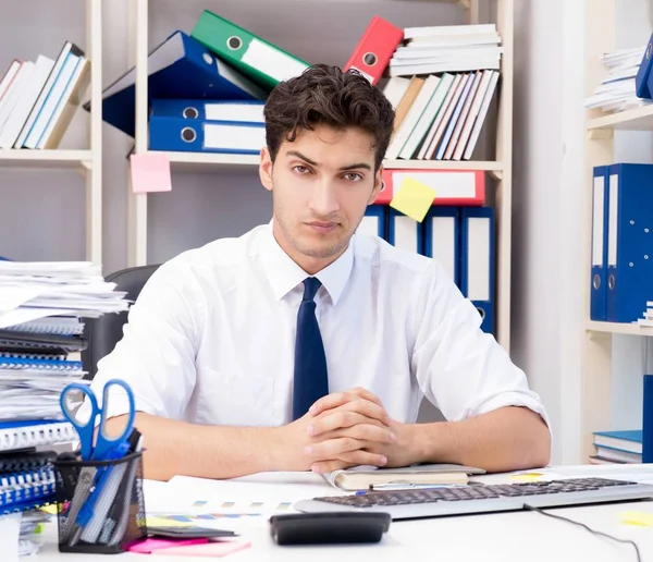 Geschäftsmann arbeitet im Büro mit Stapeln von Büchern und Papieren — Stockfoto