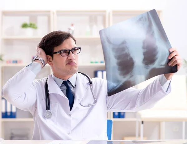 Médico joven mirando imágenes de rayos X en la clínica — Foto de Stock