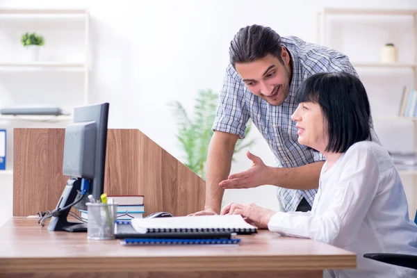 Junge männliche Mitarbeiter erklären alten Kolleginnen, wie sie zu uns kommen — Stockfoto