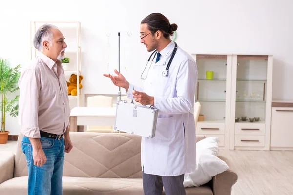 Jonge mannelijke arts bezoekt oude patiënt thuis — Stockfoto