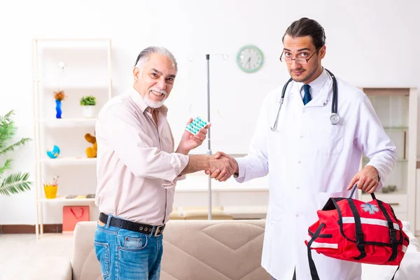 Joven médico varón visitando a paciente viejo en casa —  Fotos de Stock