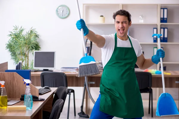 Jovem empreiteiro bonito limpando o escritório — Fotografia de Stock