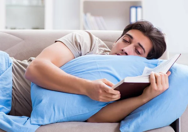 O jovem estudante se preparando para exames universitários na cama com bo — Fotografia de Stock