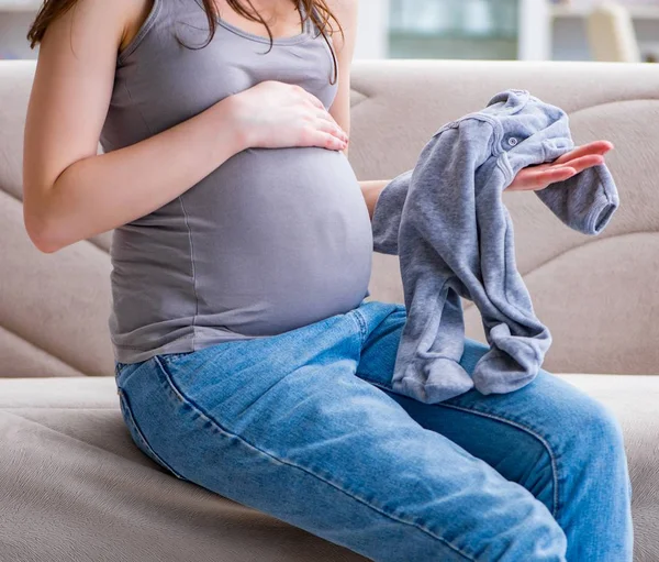 Karnında göbeği olan hamile bir kadın evdeki kanepede oturuyor. — Stok fotoğraf