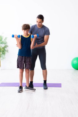 Genç baba ve oğlu egzersiz yapıyor.