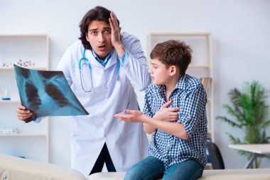 Male radiologist looking at boys images clipart