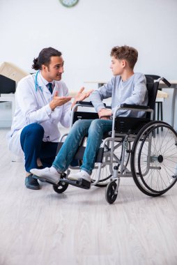 Genç erkek doktor pediatrist ve tekerlekli sandalyedeki çocuk.