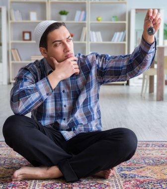 Genç Müslüman adam evde dua ediyor.