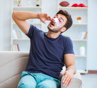 Genç adam estetik cerrahi burnundan sonra evde iyileşiyor.