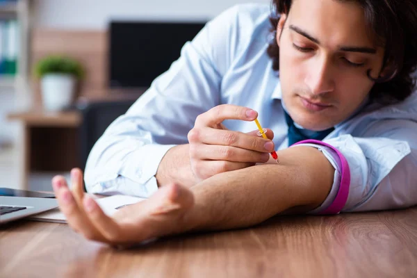 Young man having problems with narcotics at workplace — Stock Photo, Image