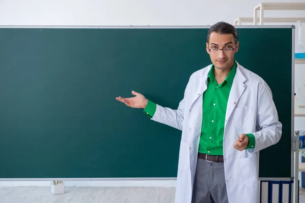 Jonge mannelijke scheikundige leraar voor schoolbord — Stockfoto