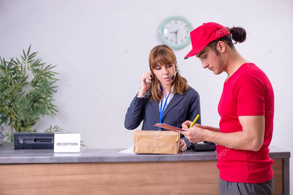 Young male courier delivering box to hotels reception