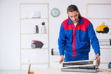 Genç erkek müteahhit atölyede klima tamiri yapıyor.