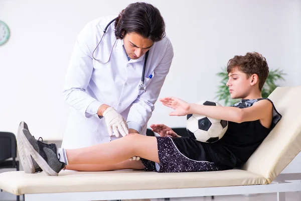 Menino jogador de futebol visitando jovem médico traumatologista — Fotografia de Stock