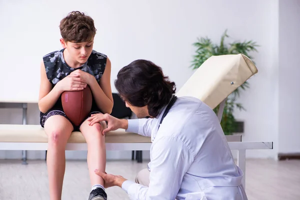 Niño jugador de fútbol americano visitando joven médico traumatologis — Foto de Stock