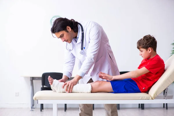 Noha zraněný chlapec návštěva mladý lékař traumatolog — Stock fotografie