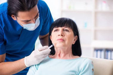 Yaşlı kadın estetik ameliyat için erkek doktoru ziyaret ediyor.