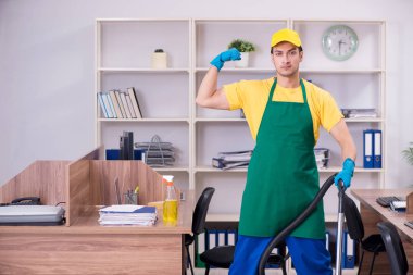 Genç müteahhit ofisi temizliyor.