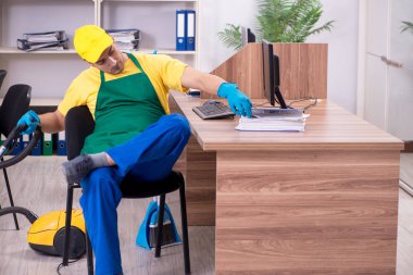 Genç müteahhit ofisi temizliyor.