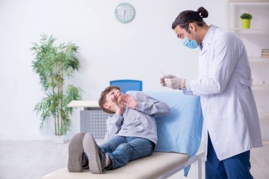 Genç çocuk hastanede doktoru ziyaret ediyor.