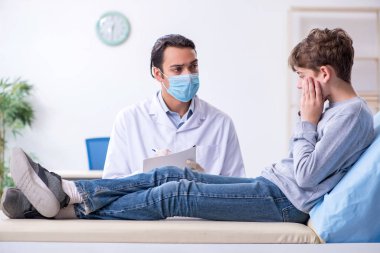 Genç çocuk hastanede doktoru ziyaret ediyor.